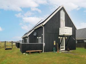 un granero negro con un banco delante en 9 person holiday home in Thisted, en Nørre Vorupør