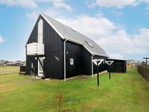 une grange noire avec un toit métallique sur un champ dans l'établissement 9 person holiday home in Thisted, à Nørre Vorupør