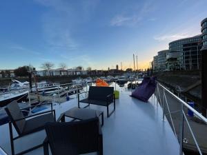 eine Terrasse mit Stühlen, Tischen und Booten in einem Yachthafen in der Unterkunft Hausboot Lore in Duisburg