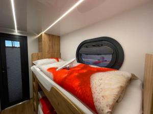 een slaapkamer met een bed met een oranje deken bij Hausboot Lore in Duisburg