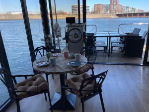 einen Tisch und Stühle auf einer Terrasse mit Blick auf das Wasser in der Unterkunft Hausboot Lore in Duisburg