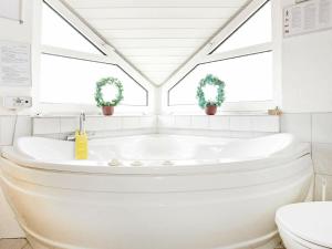 a white bathroom with a tub and two windows at 10 person holiday home in Thisted in Klitmøller