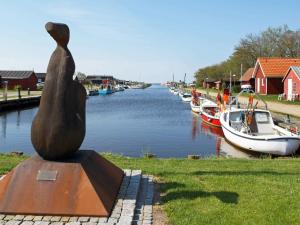 a statue sitting next to a river with boats at 4 person holiday home in Skjern in Lem
