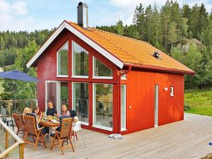 una familia sentada en una mesa frente a un cobertizo rojo en Holiday Home Dalby, en Henån