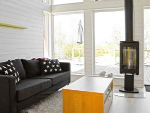 sala de estar con sofá negro y chimenea en Holiday Home Dalby, en Henån