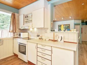 a kitchen with white cabinets and white appliances at 8 person holiday home in Bl vand in Ho