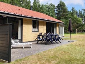 a group of chairs and an umbrella in front of a building at 8 person holiday home in Bl vand in Ho