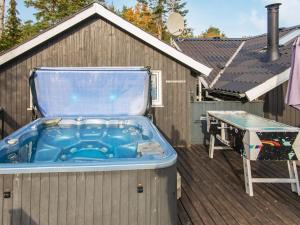 bañera de hidromasaje en una terraza junto a una mesa en 6 person holiday home in Ebeltoft, en Øksenmølle