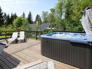 bañera de hidromasaje en una terraza con 2 sillas en 6 person holiday home in Ebeltoft, en Øksenmølle