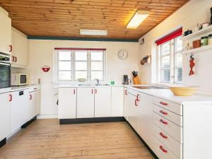 cocina con armarios blancos y techo de madera en 7 person holiday home in Bl vand, en Blåvand
