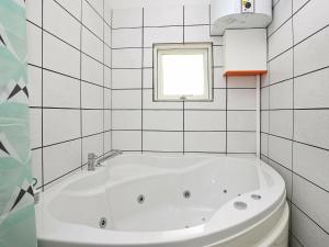 ロッケンにあるThree-Bedroom Holiday home in Løkken 78の白いタイル張りのバスルーム(白いバスタブ、窓付)