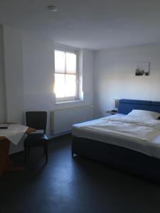 een slaapkamer met een bed, een raam en een stoel bij Hotel-Restaurant zur Post in Wabern