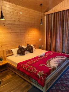 a large bed in a room with wooden walls at WildWoodHome Jibhi in Jibhi