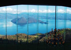 a view of a lake from a glass window at The Windsor Hotel TOYA Vignette Collection in Lake Toya