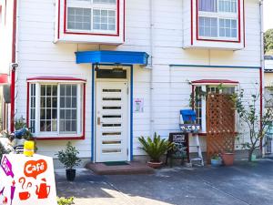 uma casa branca com uma porta azul e janelas vermelhas em Guest House Shirahama R-cafe - Female Only em Shirahama