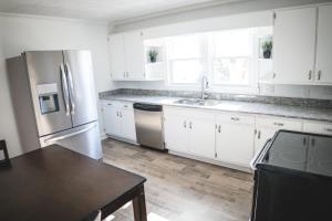 a kitchen with white cabinets and a stainless steel refrigerator at Modern Cottage Near Hospitals and Brewery! in Morganton