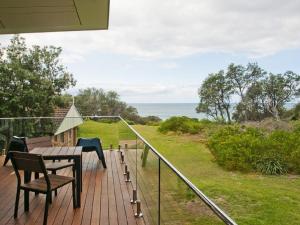 a deck with a table and chairs and a view of the ocean at Farrant House in Culburra Beach