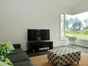 a living room with a couch and a tv at Farrant House in Culburra Beach