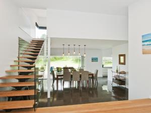 a dining room and kitchen with a staircase and a dining table at Farrant House in Culburra Beach