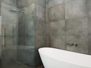 a bathroom with a tub and a glass shower at Farrant House in Culburra Beach +20 photos