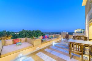 a rooftop patio with couches and tables and chairs at Hotel Jasmin Home in Jaisalmer