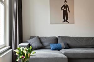a living room with a gray couch and a picture of a man at Residences Jordan Canal in Amsterdam