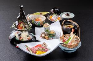 中津川温泉　ホテル花更紗 في Ochiai: مجموعة من أطباق الطعام على طاولة