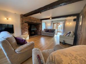 a living room with two couches and a fireplace at Eco-friendly Dorset cottage with spa set in heart of countryside in Sydling St Nicholas