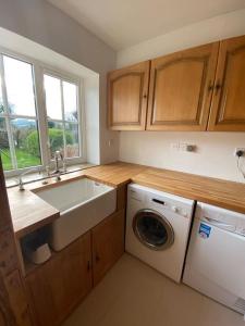 a kitchen with a sink and a washing machine at Eco-friendly Dorset cottage with spa set in heart of countryside in Sydling St Nicholas