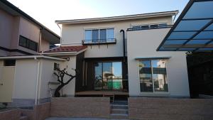 a white house with glass windows and stairs at Guesthouse Gifu SUAI in Gifu