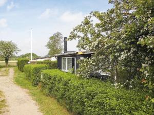 una pequeña casa en un seto al lado de un camino de tierra en 4 person holiday home in Broager en Broager