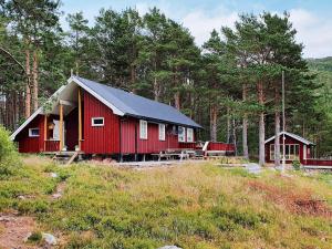 a red cabin with a black roof in a forest at 8 person holiday home in Sundlandet in Snildal