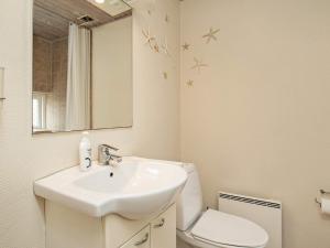 ein Badezimmer mit einem Waschbecken, einem WC und einem Spiegel in der Unterkunft 4 person holiday home in r sk bing in Ærøskøbing
