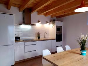 a kitchen with white cabinets and a wooden table at Los Olmos Alojamiento Rural in Los Olmos