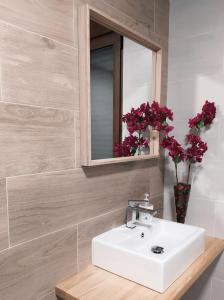 a bathroom with a sink and a mirror and flowers at Los Olmos Alojamiento Rural in Los Olmos +21 photos
