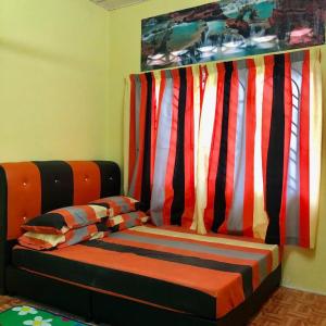 太平HOMESTAY CIK MUNAH的色彩缤纷的窗帘间的一张床