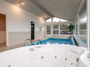 a bathroom with a tub and a swimming pool at 12 person holiday home in L kken in Grønhøj