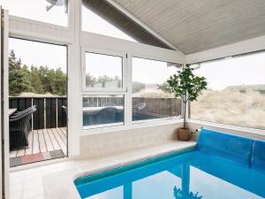 eine abgeschirmte Veranda mit einem Pool und Fenstern in der Unterkunft 12 person holiday home in L kken in Grønhøj