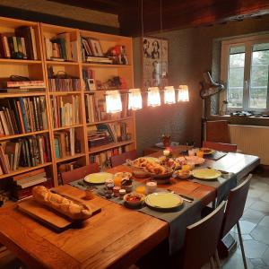 una mesa de madera con comida en una habitación con libros en Chambre d'hôte Le Châtaignier, en Planchez