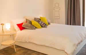 a white bed with colorful pillows on it at Aveiro Urban Flat in Aveiro