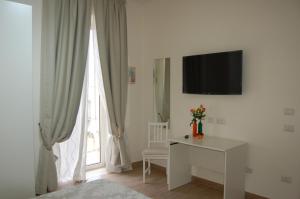 拿坡里的住宿－La terrazza delle fate，白色的客房设有书桌、电视和窗户。