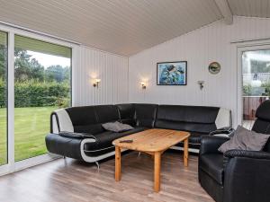 Una sala de estar con un sofá negro y una mesa. en 8 person holiday home in Væggerløse-By Traum, en Bøtø By