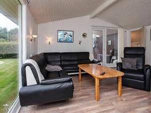 a living room with a black couch and a table at Holiday home Væggerløse II in Marielyst