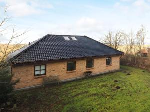 a brick house with a black roof on a field at 10 person holiday home in H jslev in Højslev