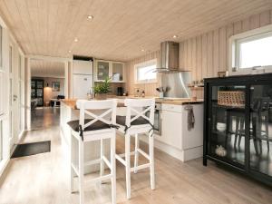 una cucina con sgabelli bianchi e bancone di 12 person holiday home in L kken a Løkken