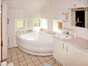 a white bathroom with a tub and two sinks at 6 person holiday home in Hemmet in Hemmet