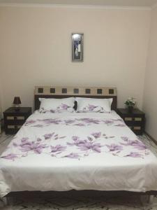 Una cama con flores moradas en un dormitorio en Apartament simplu si confortabil, en Chişinău
