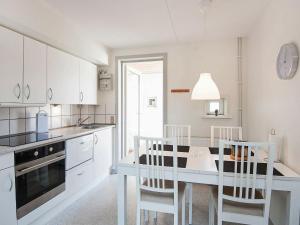SønderbyにあるHoliday home Rømø XIの白いキャビネット、テーブルと椅子付きのキッチンが備わります。