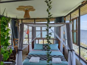 Ce lit se trouve dans un dortoir offrant une vue sur l'océan. dans l'établissement Avocado Bay Private Retreat, à Entebbe