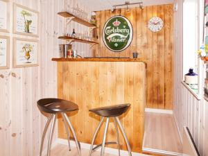 a bar with two stools in front of a wooden wall at 6 person holiday home in Hemmet in Hemmet